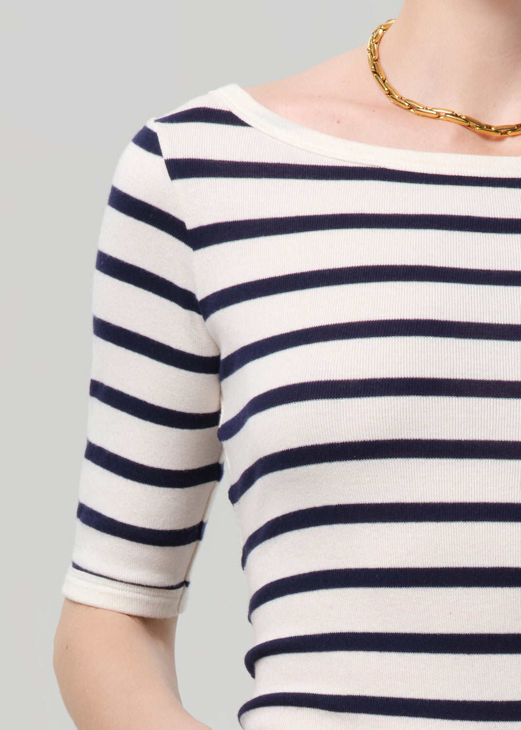 Navy and white striped shirt worn by a person on a gray background