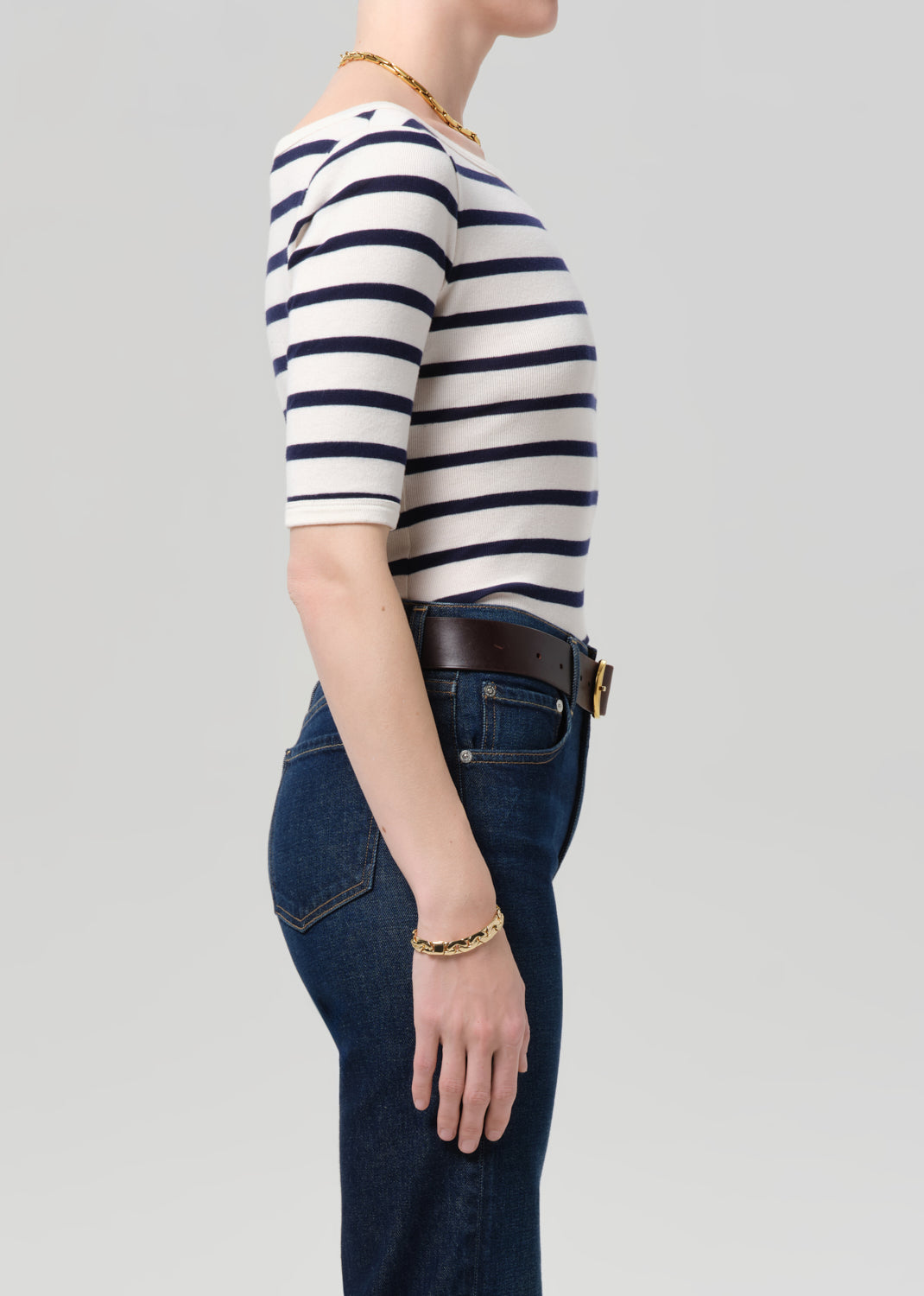 Person wearing a striped shirt and jeans on a plain background
