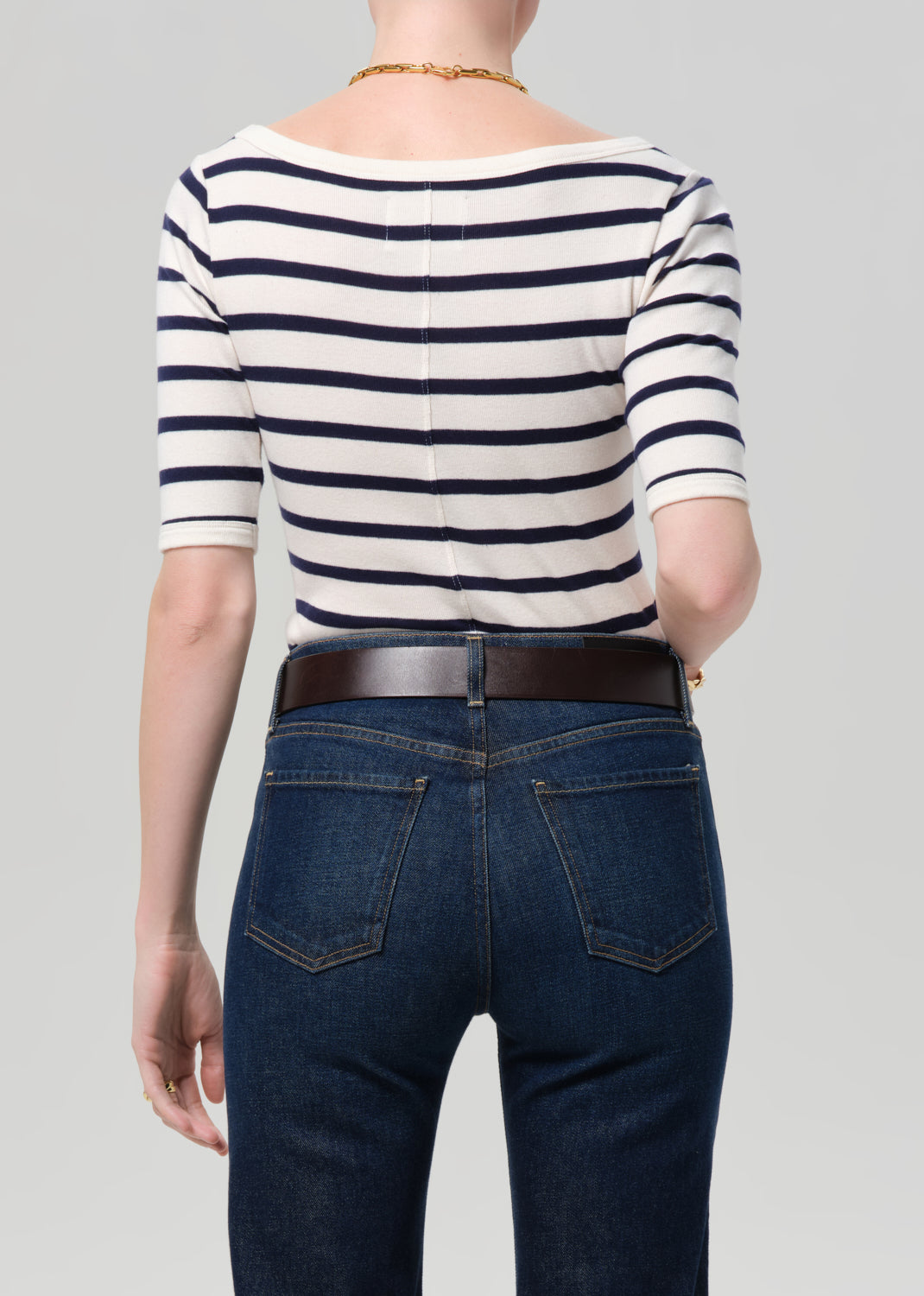 Person wearing a striped shirt and jeans on a plain background