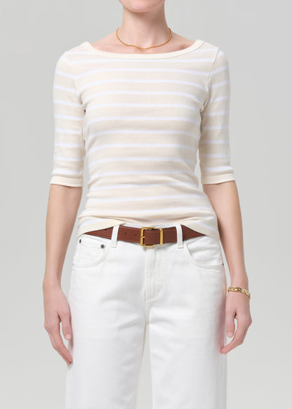 Person wearing a striped shirt and white pants with a brown belt on a plain background