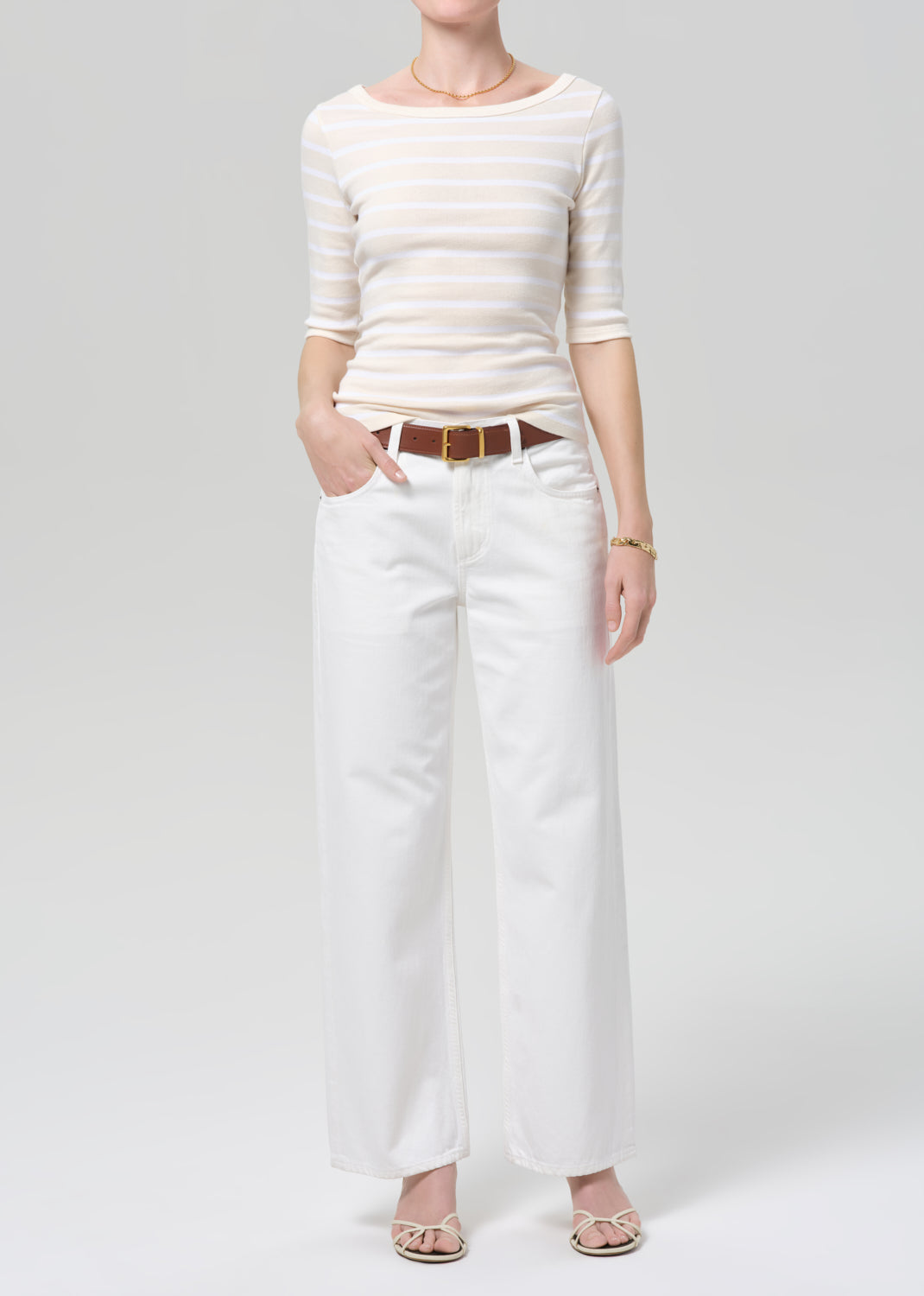 Person wearing a white striped shirt and white pants on a plain background