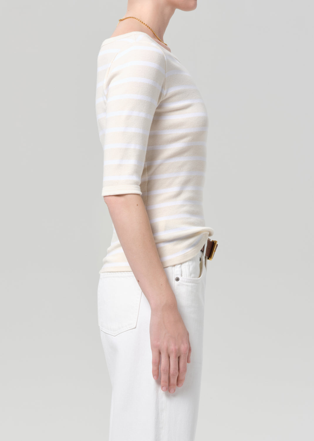 Person wearing a white and beige striped shirt with a plain background