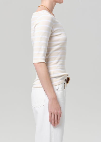 Person wearing a white and beige striped shirt with a plain background