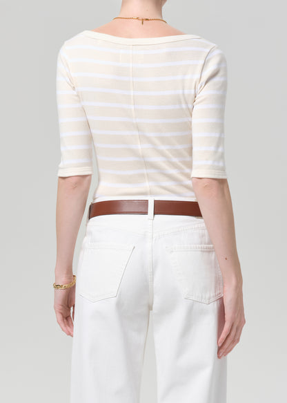 Person wearing a striped shirt and white pants with a brown belt on a gray background