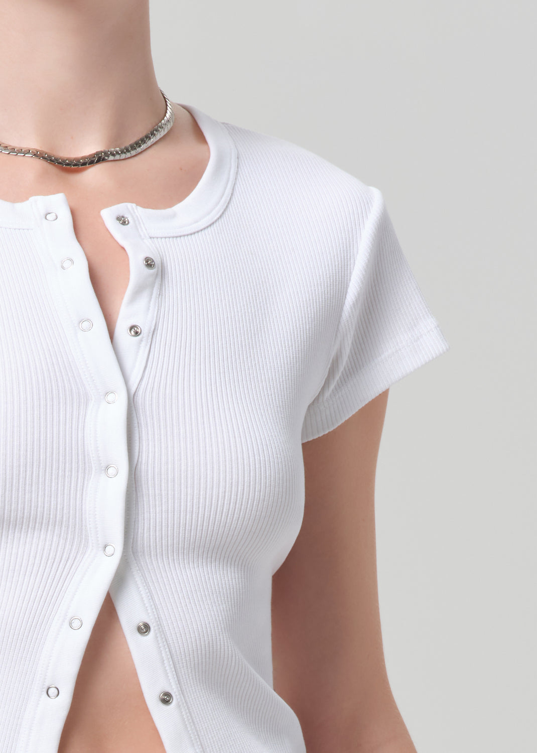 White ribbed knit cardigan worn by a person on a plain background