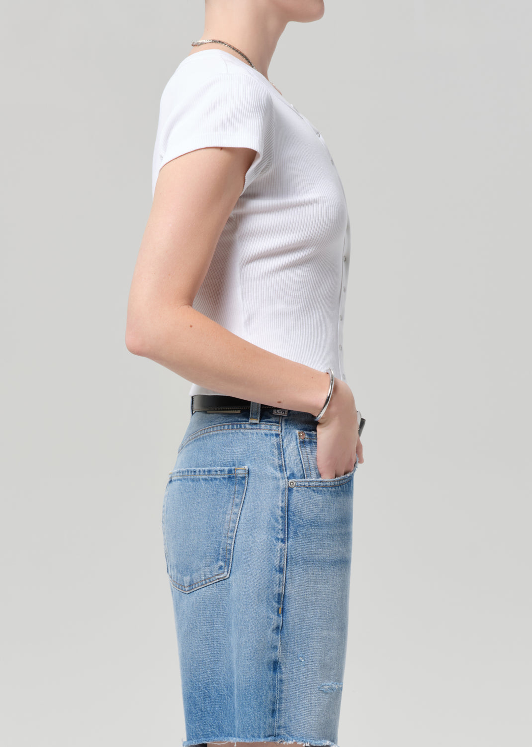 Person wearing a white t-shirt and blue jeans on a plain background