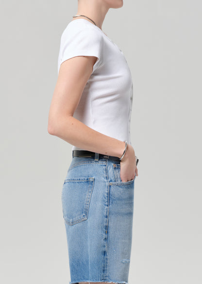 Person wearing a white t-shirt and blue jeans on a plain background