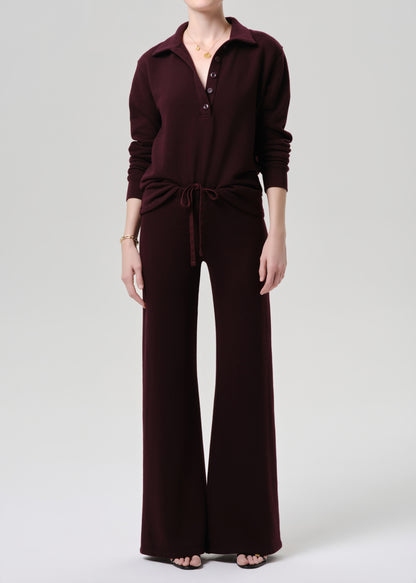 Person wearing a maroon jumpsuit on a grey background
