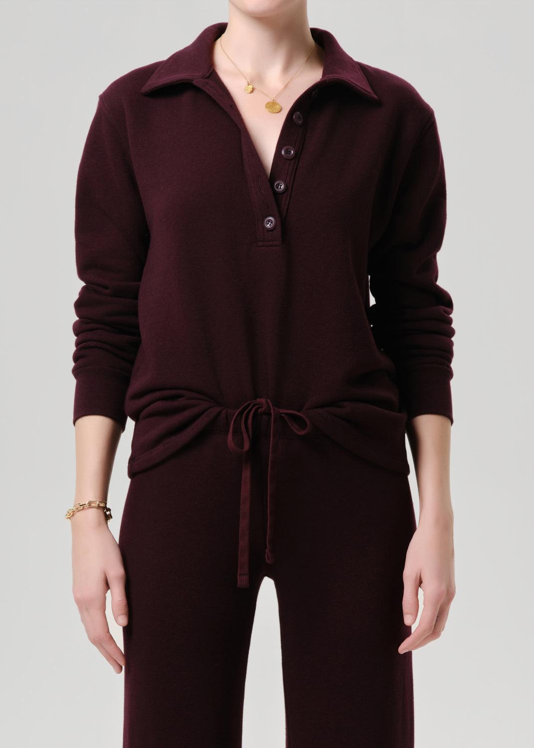 Maroon jumpsuit worn by a person on a grey background