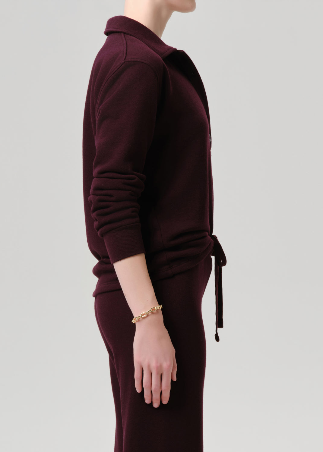Maroon dress with long sleeves and a belt on a grey background