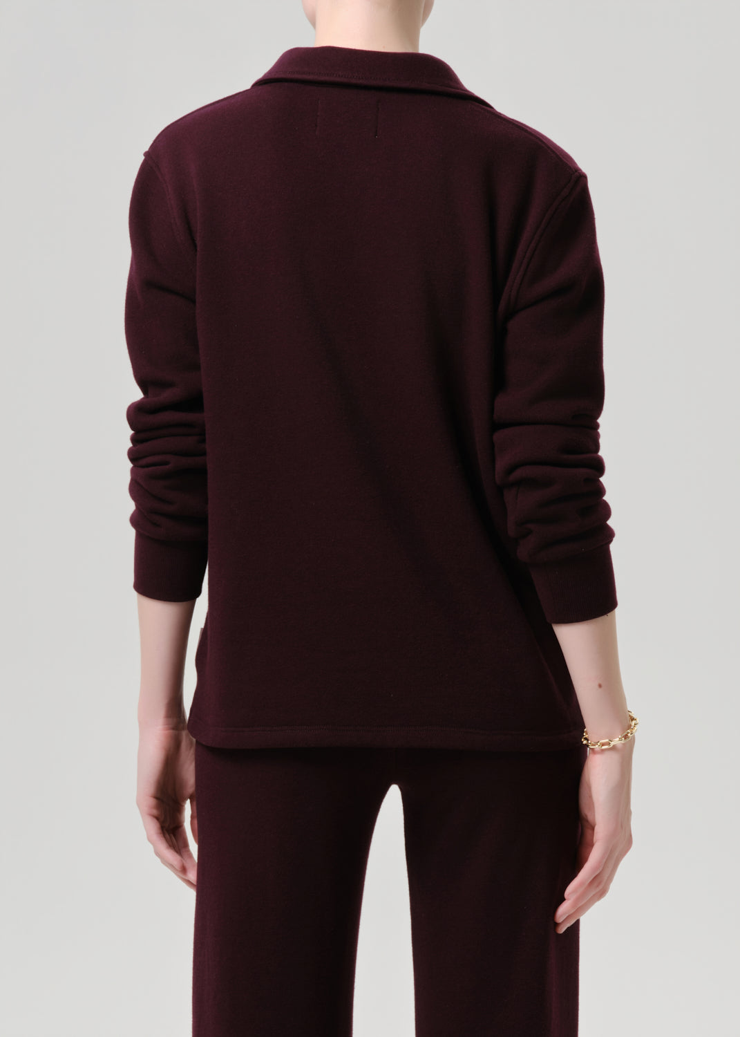 Person wearing a dark brown outfit on a grey background
