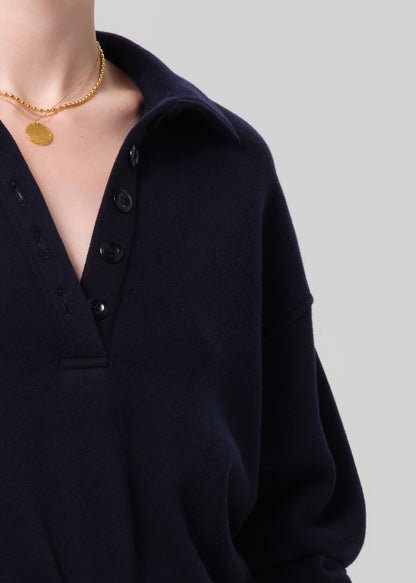 Person wearing a navy outfit with a matching sweatshirt and shorts on a gray background