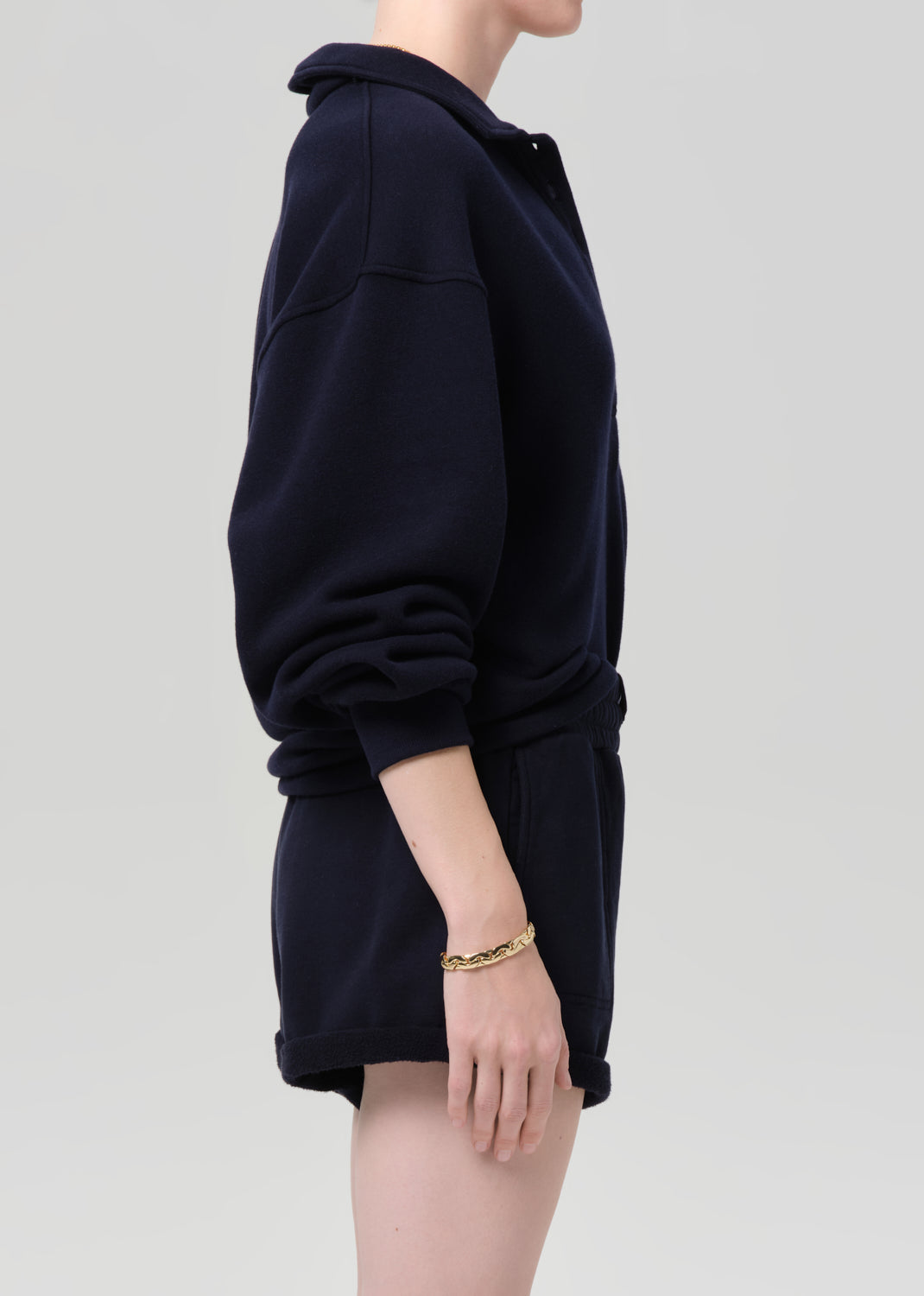 Person wearing a navy outfit with a matching sweatshirt and shorts on a gray background