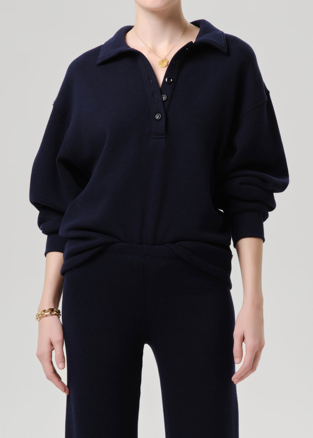Person wearing a navy blue sweater and pants on a grey background.