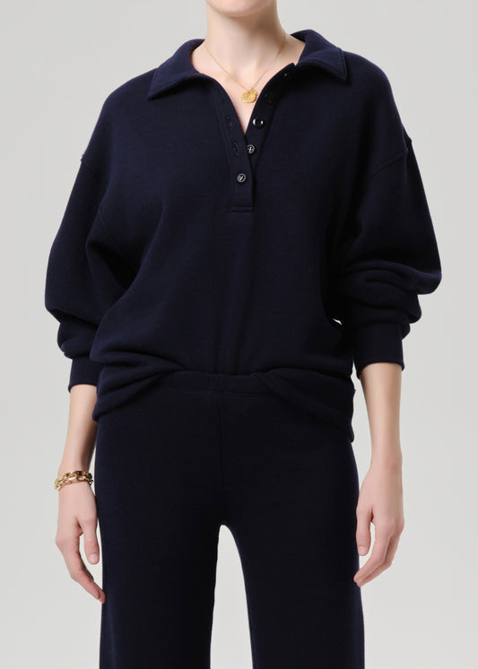 Person wearing a navy blue sweater and pants on a grey background.
