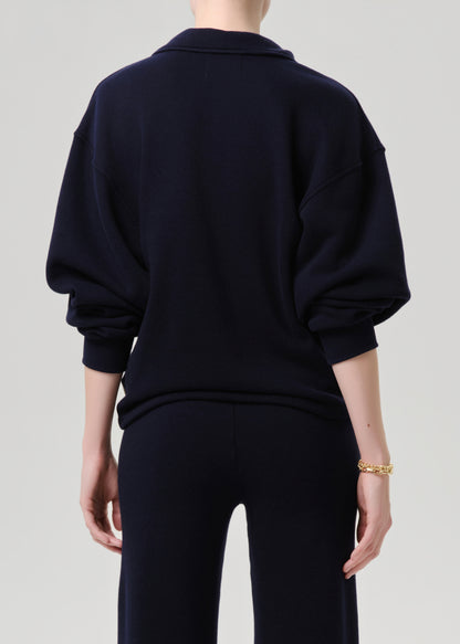 Person wearing a navy blue sweater and pants on a grey background.