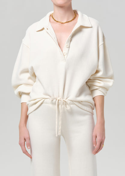 Person wearing a cream-colored outfit with a plain background