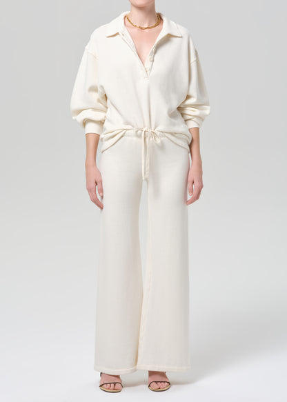 Person wearing a cream-colored sweatshirt and pants on a plain background