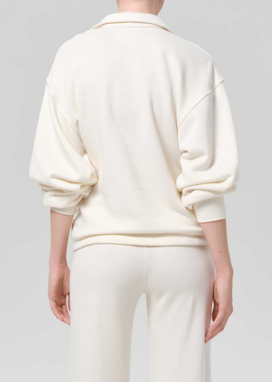 Person wearing a cream-colored outfit on a plain background
