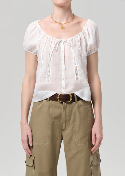 Person wearing a white blouse and beige pants on a gray background