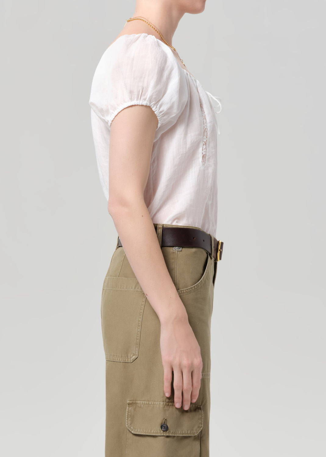 Person wearing a white shirt and beige cargo pants on a plain background