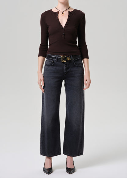 Person wearing a brown top and black wide-leg jeans on a grey background