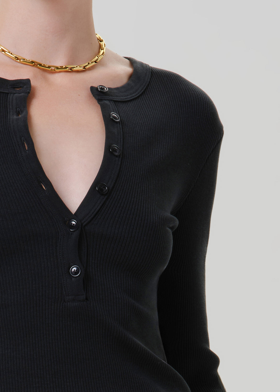 Close-up of black long sleeve henley top showing the button-front neckline and ribbed texture.