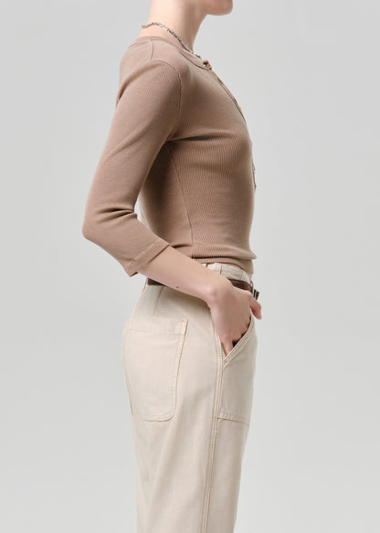 Person wearing a beige sweater and pants on a grey background