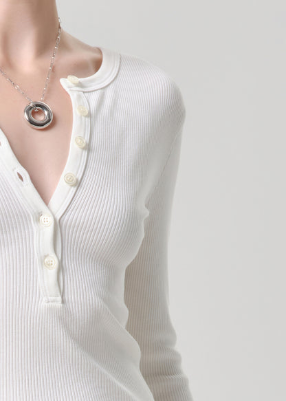 White long-sleeve shirt with buttons and a necklace on a grey background
