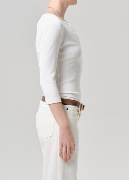 Person wearing a white long-sleeve top and white pants on a grey background