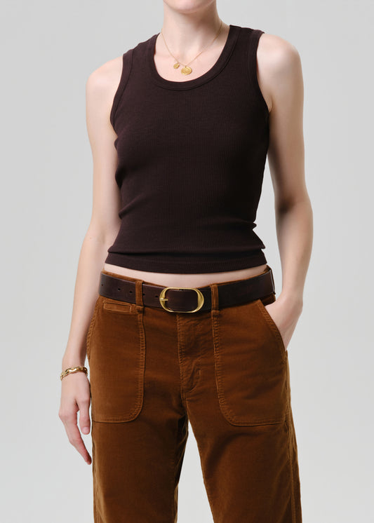 Person wearing a brown tank top and brown pants on a grey background