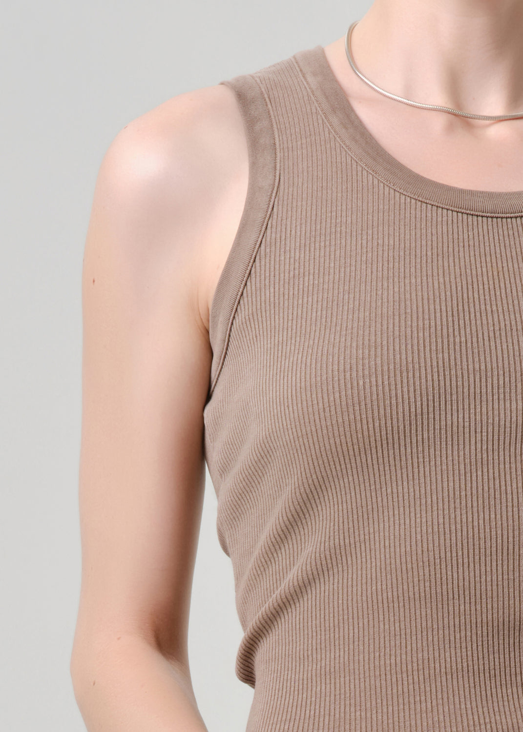 Brown ribbed tank top worn by a person on a grey background