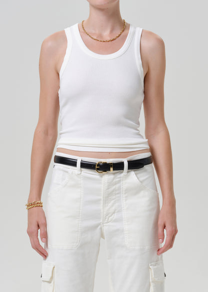 A model wearing a white ribbed tank top and white cargo pants, styled with a black belt with a gold buckle.
