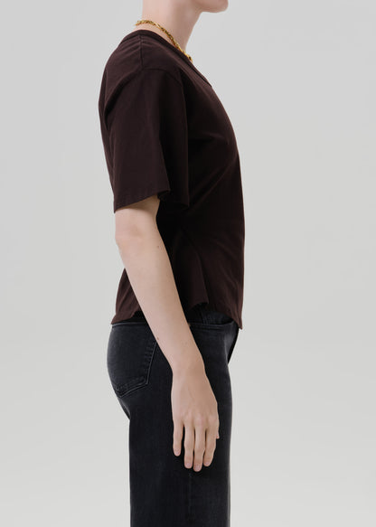 Person wearing a dark brown short sleeve knit top with a crew neckline on a grey background