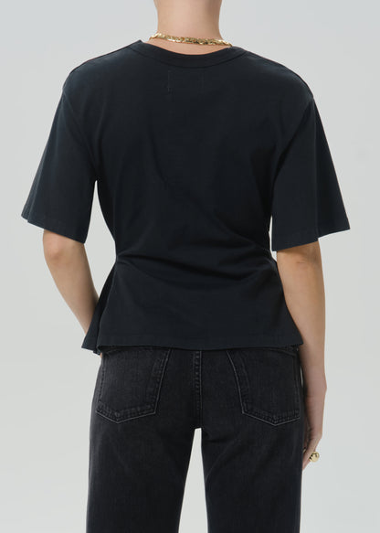 Rear view of a person wearing a black short-sleeve crew-neck T-shirt and dark jeans against a grey background.