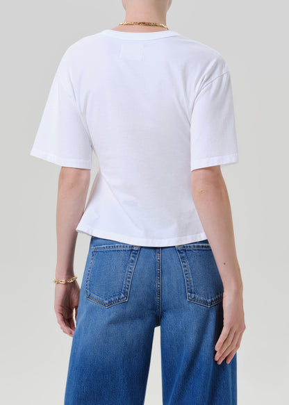 A person shown from the back wearing a plain white short-sleeve T-shirt and blue jeans against a grey background.