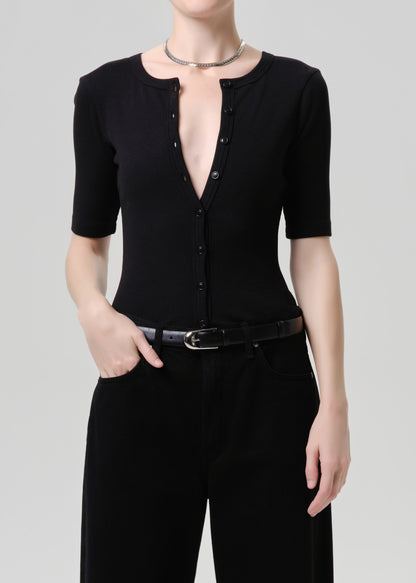 Person wearing a black top and black pants on a grey background