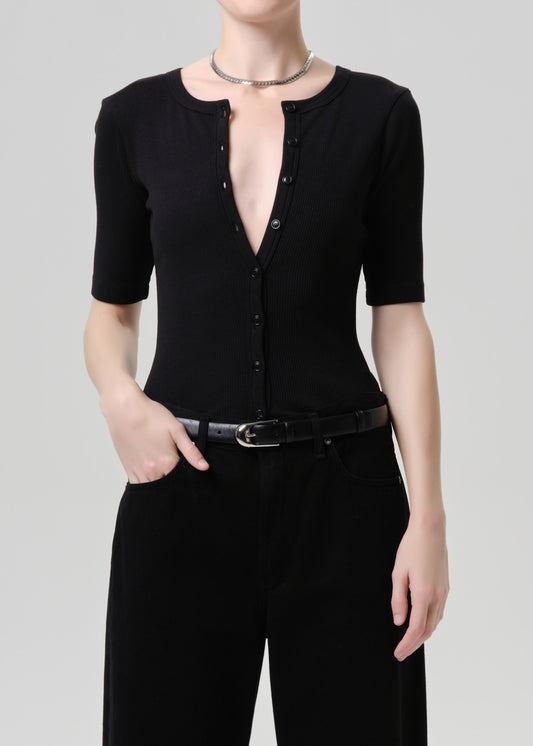 Person wearing a black top and black pants on a grey background