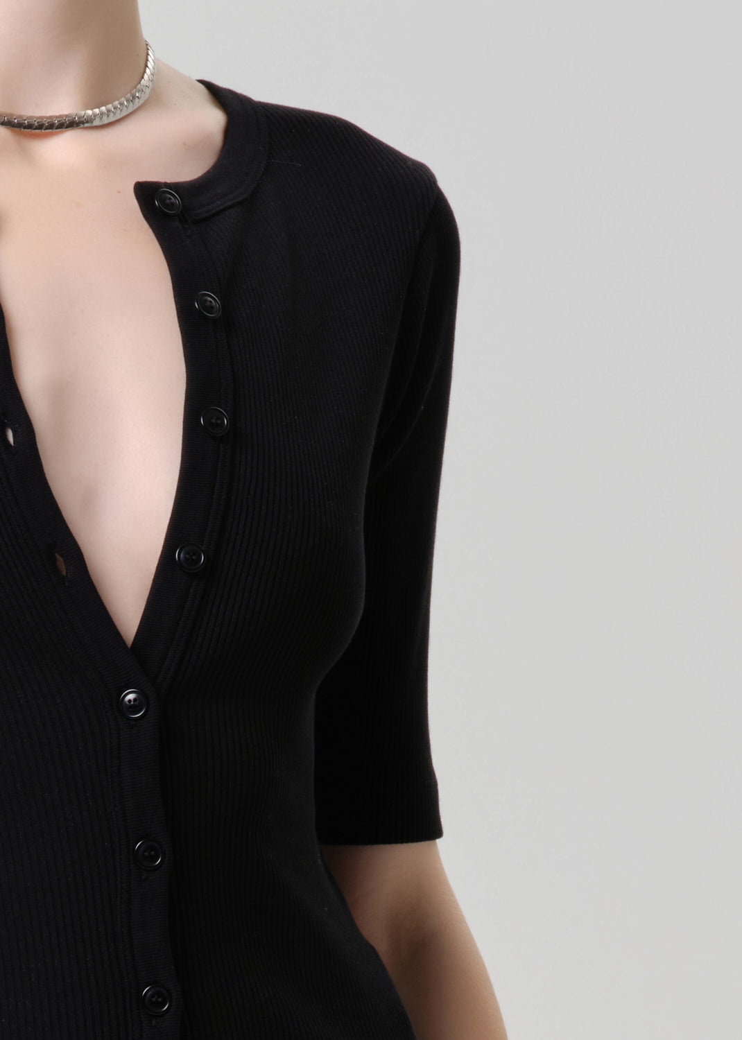 Black cardigan with a plunging neckline against a grey background