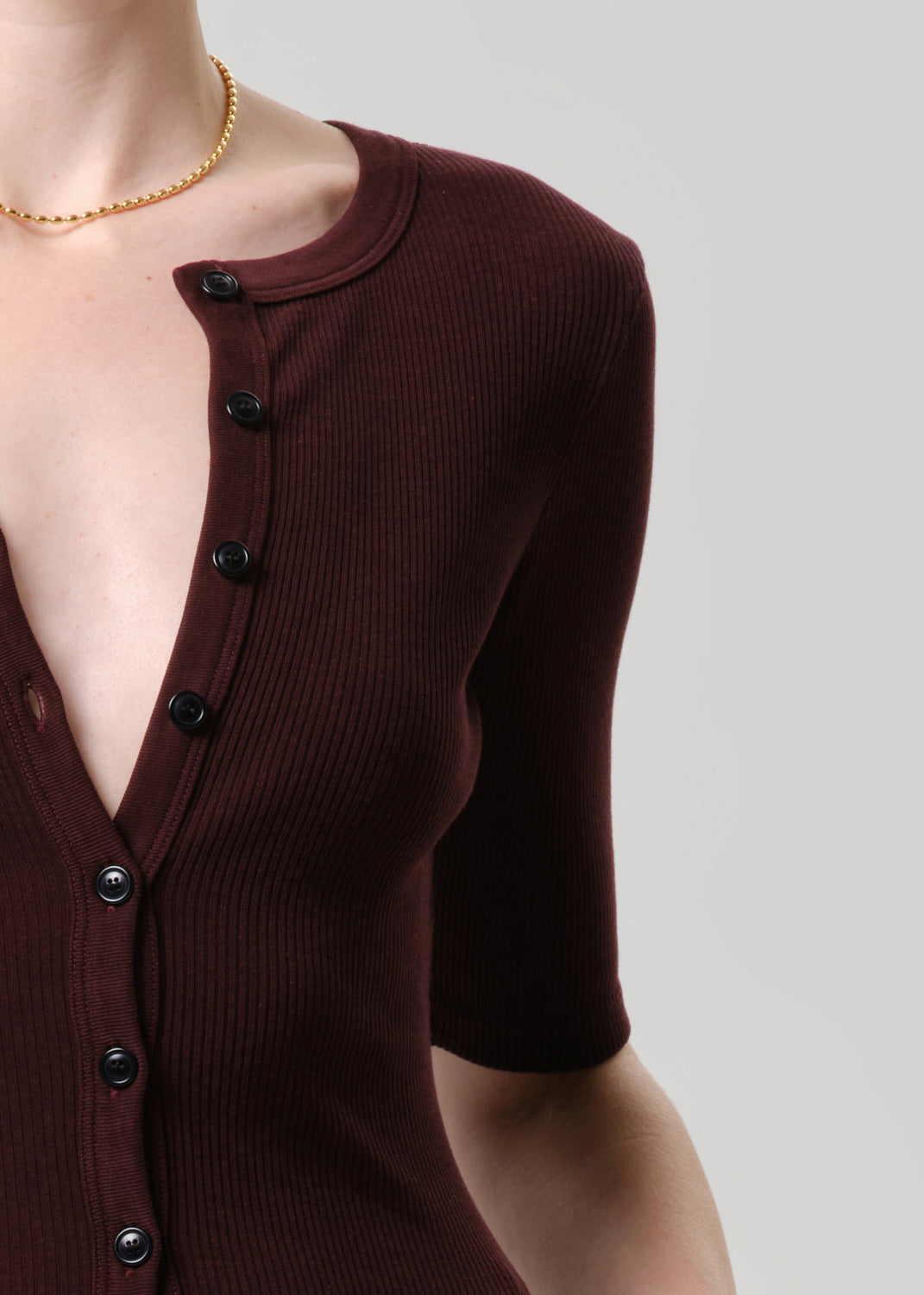 Brown ribbed sweater with black buttons on a grey background