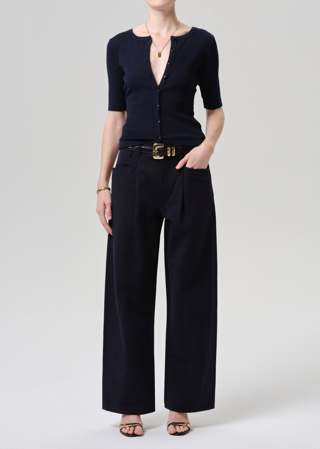 Person wearing a navy blue outfit with wide-leg pants on a grey background