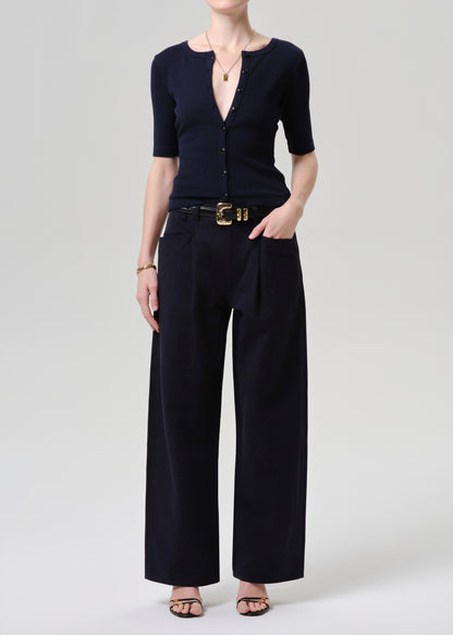 Person wearing a navy blue outfit with wide-leg pants on a grey background