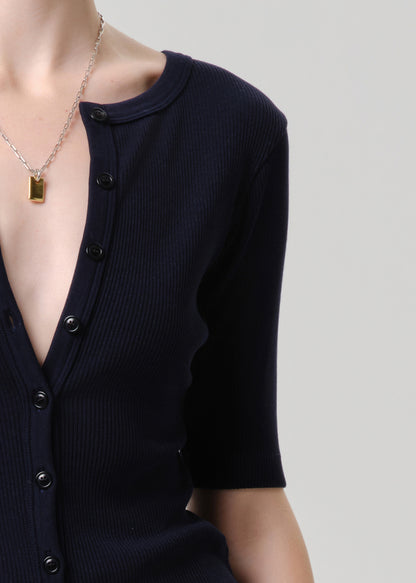 Navy blue cardigan with a necklace on a grey background