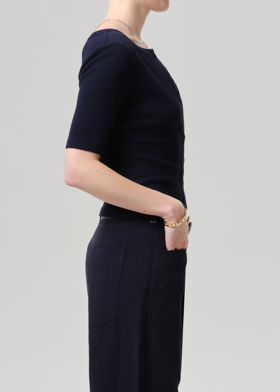Person wearing a navy blue top and pants on a grey background