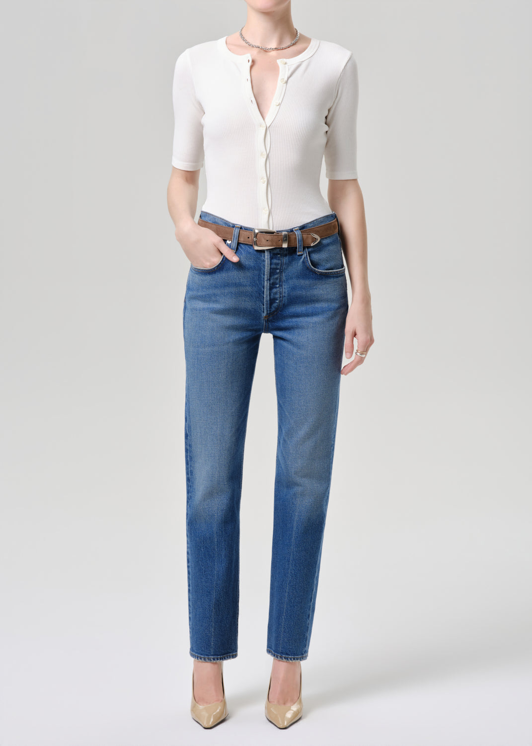 Person wearing a white shirt and blue jeans on a grey background