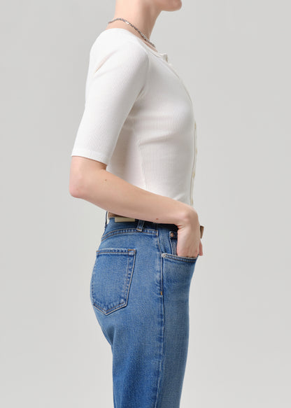 Person wearing a white top and blue jeans on a light grey background