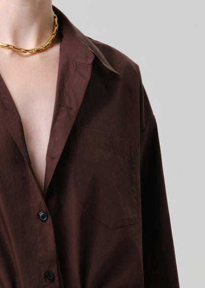 Brown shirt with a gold chain necklace on a grey background