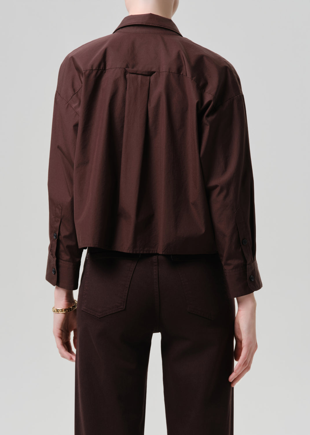 Brown jacket and pants worn by a person on a grey background