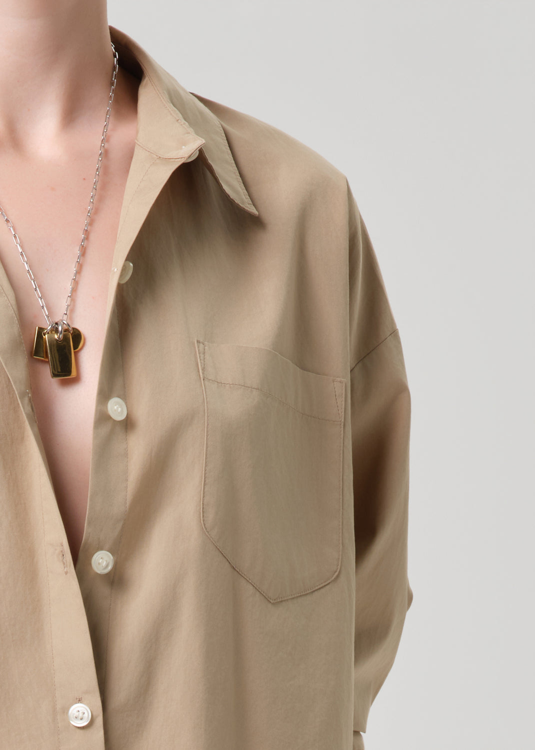 Beige shirt with a necklace on a grey background
