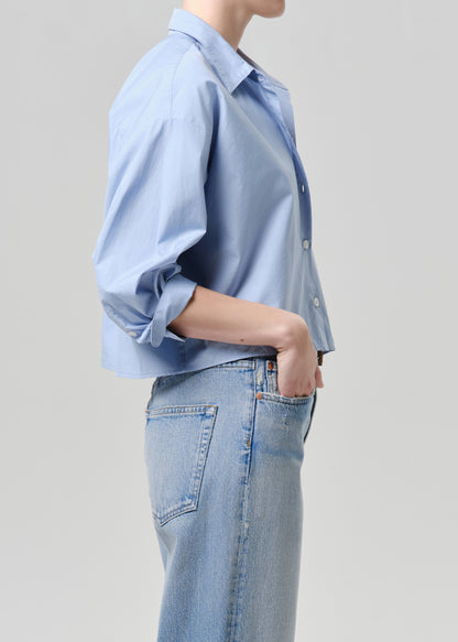 Person wearing a light blue shirt and jeans on a grey background